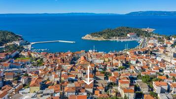 A coastal town with dense red-roofed buildings, a marina, and a prominent lighthouse.