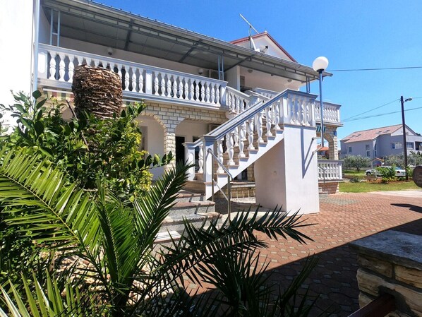 Un bâtiment à deux étages, doté d’un balcon blanc et d’un escalier menant à l’étage supérieur.