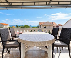 A covered outdoor patio with a round table and four chairs. - Apartments Ana (Sukosan)