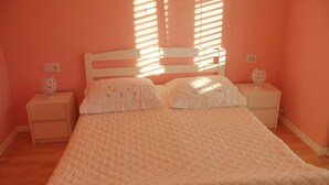 A bedroom with a bed, two nightstands, and a window with blinds. - Apartments Mirjana (Pakostane)