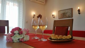 Ein Esstisch mit roter Tischdecke, zwei Weingläsern, einem Rosenstrauß und einer Schokoladentafel.