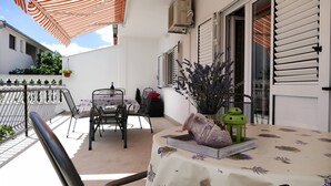 Ein Balkon mit Tisch für zwei Personen, einem Stuhl, einer hängenden Pflanze und einem dekorativen Keramikobjekt.
