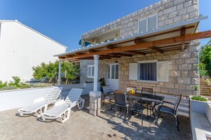 Un edificio in pietra con un balcone, poltrone e un tavolo con sedie.
