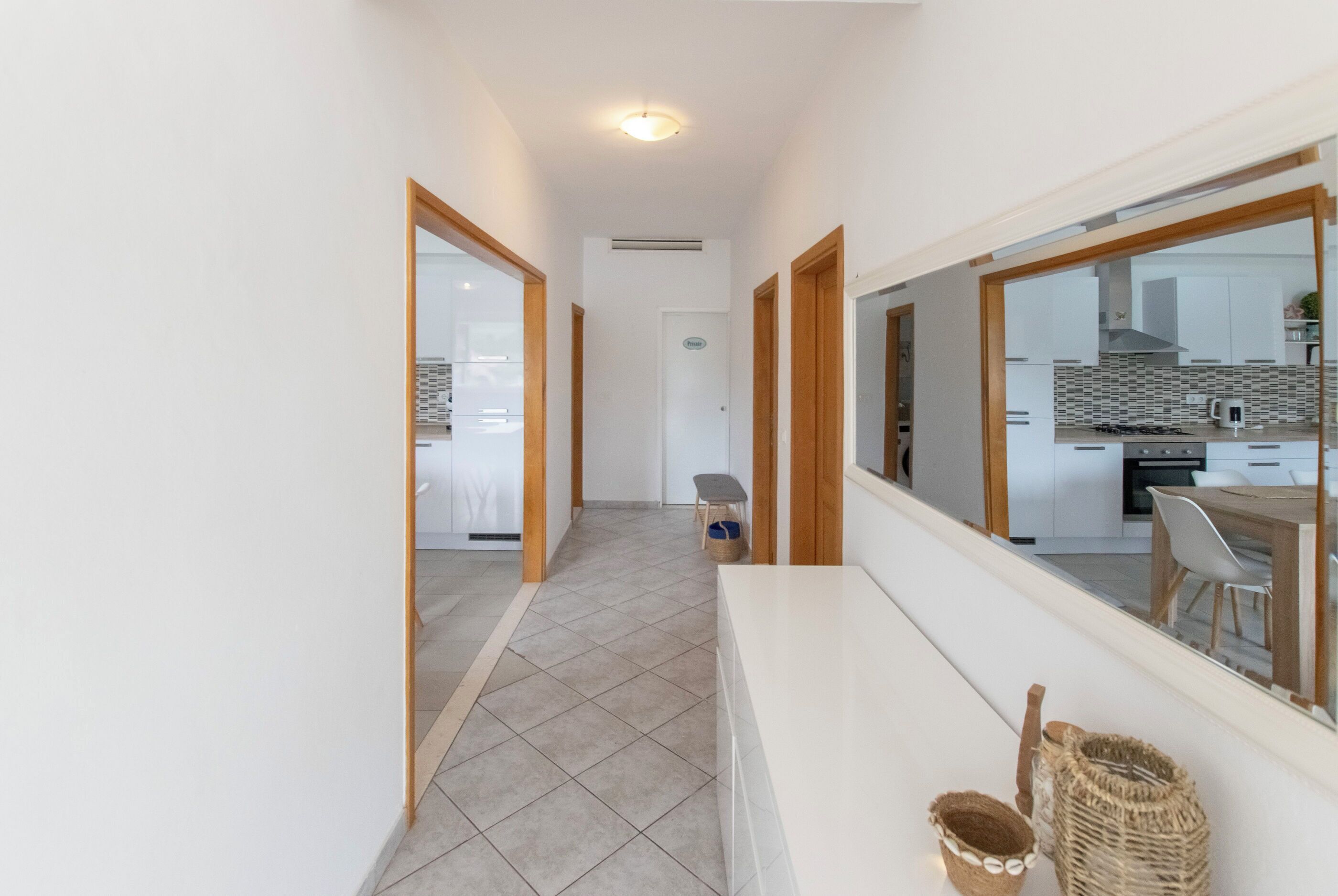 A narrow hallway with a view into a modern kitchen area.