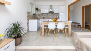 Een moderne keuken met witte kastjes, een houten eettafel en een schaal fruit.