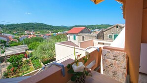 A balcony with a view of a village, a wicker basket with flowers, and a wooden table. - Apartment Neno (Preko)