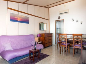 A living room with a purple sofa, a wooden coffee table, and a dining area with wooden chairs and a glass table. - House Ani (Solta)
