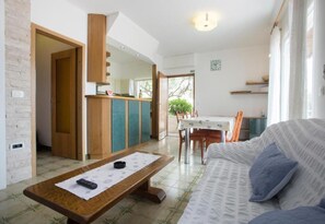 A modern living room with a sofa, a wooden coffee table, and a dining area with a table and chairs. - Apartments Damir (Postira)