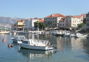 A marina with several boats docked, surrounded by buildings with red-tiled roofs. - Apartments Damir (Postira)