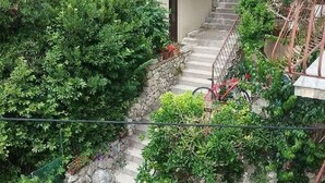 A residential area with a staircase leading to a house, surrounded by dense greenery and a parked car. - Apartment Bianca (Podgora)