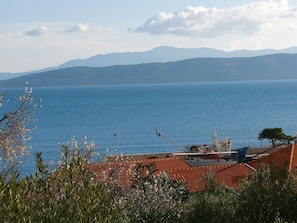 Blick auf die Küste mit einem Boot, das an einem Gebäude mit roten Ziegeldach liegt.