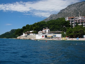 Ein Küstenhotel mit Meerblick und einer Bergkulisse.