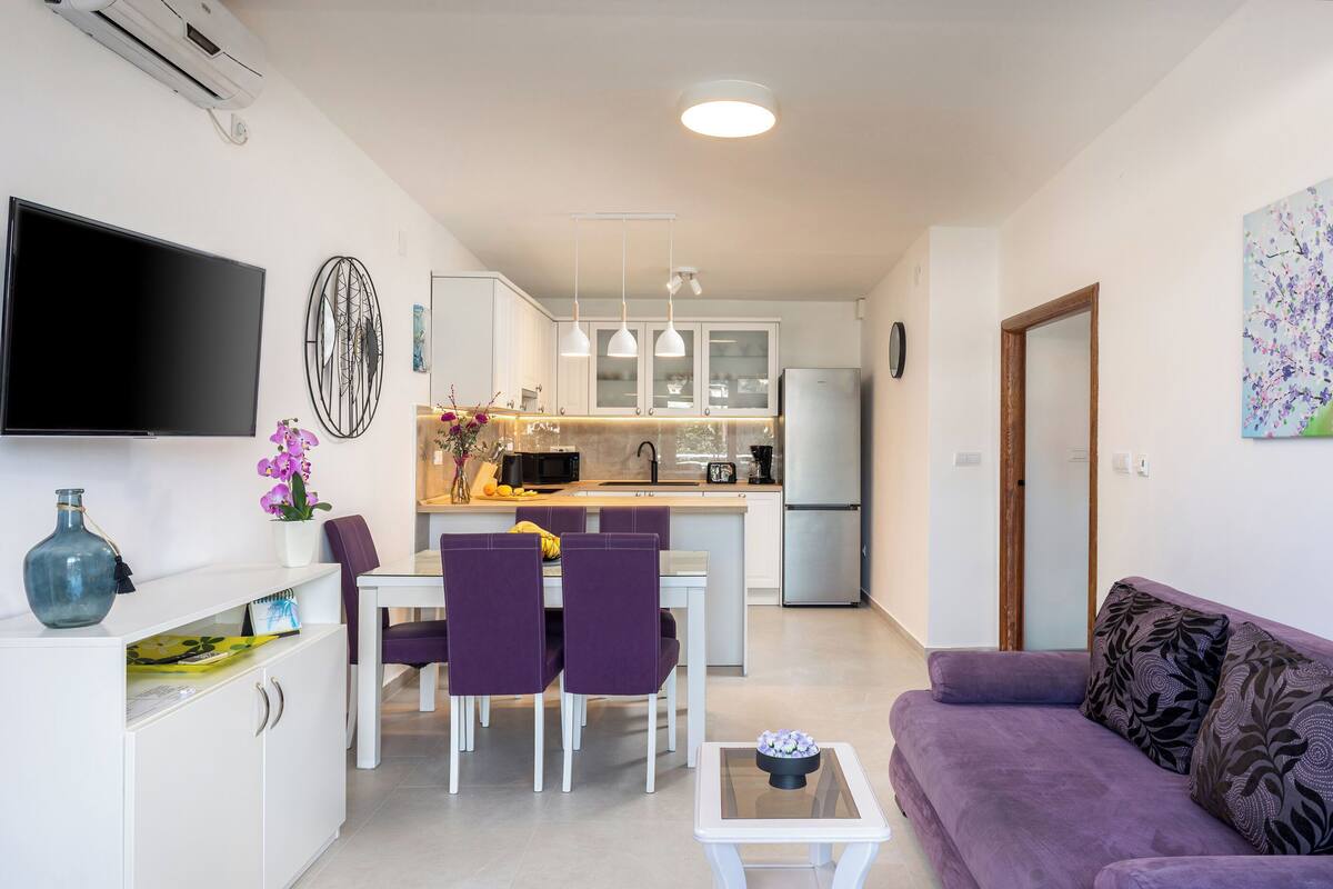 Una cocina moderna con armarios blancos, un refrigerador de acero inoxidable e iluminación colgante.
