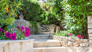 A stone staircase leading up to a garden area with vibrant flowers and lush greenery. - Apartments Star 2 (Dubrovnik)