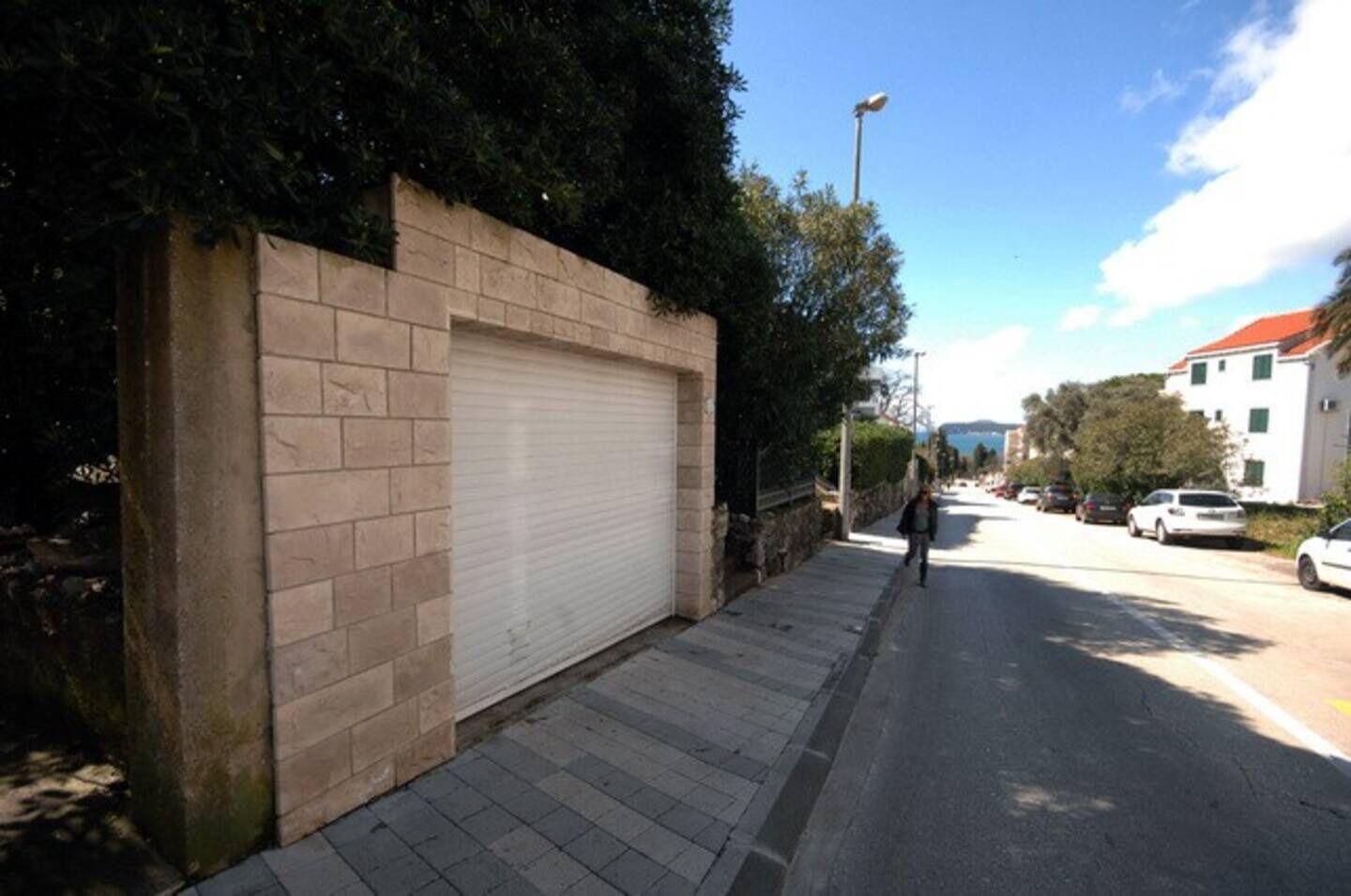 Eine Straße mit geschlossenem Garagentor, einem Bürgersteig und geparkten Autos.