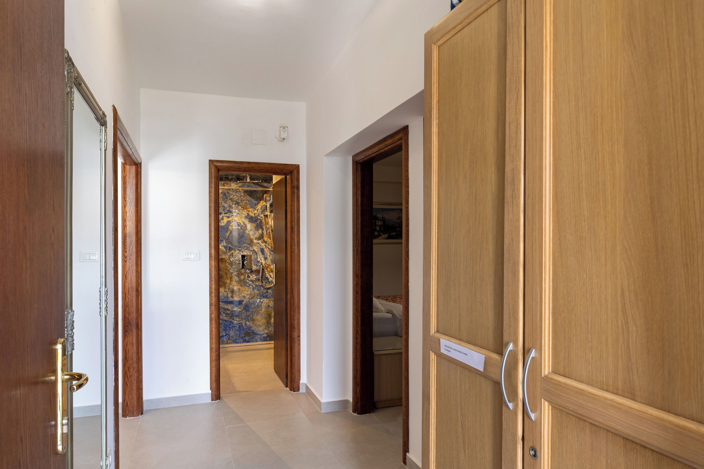 Un couloir avec des portes en bois et un mur en marbre.