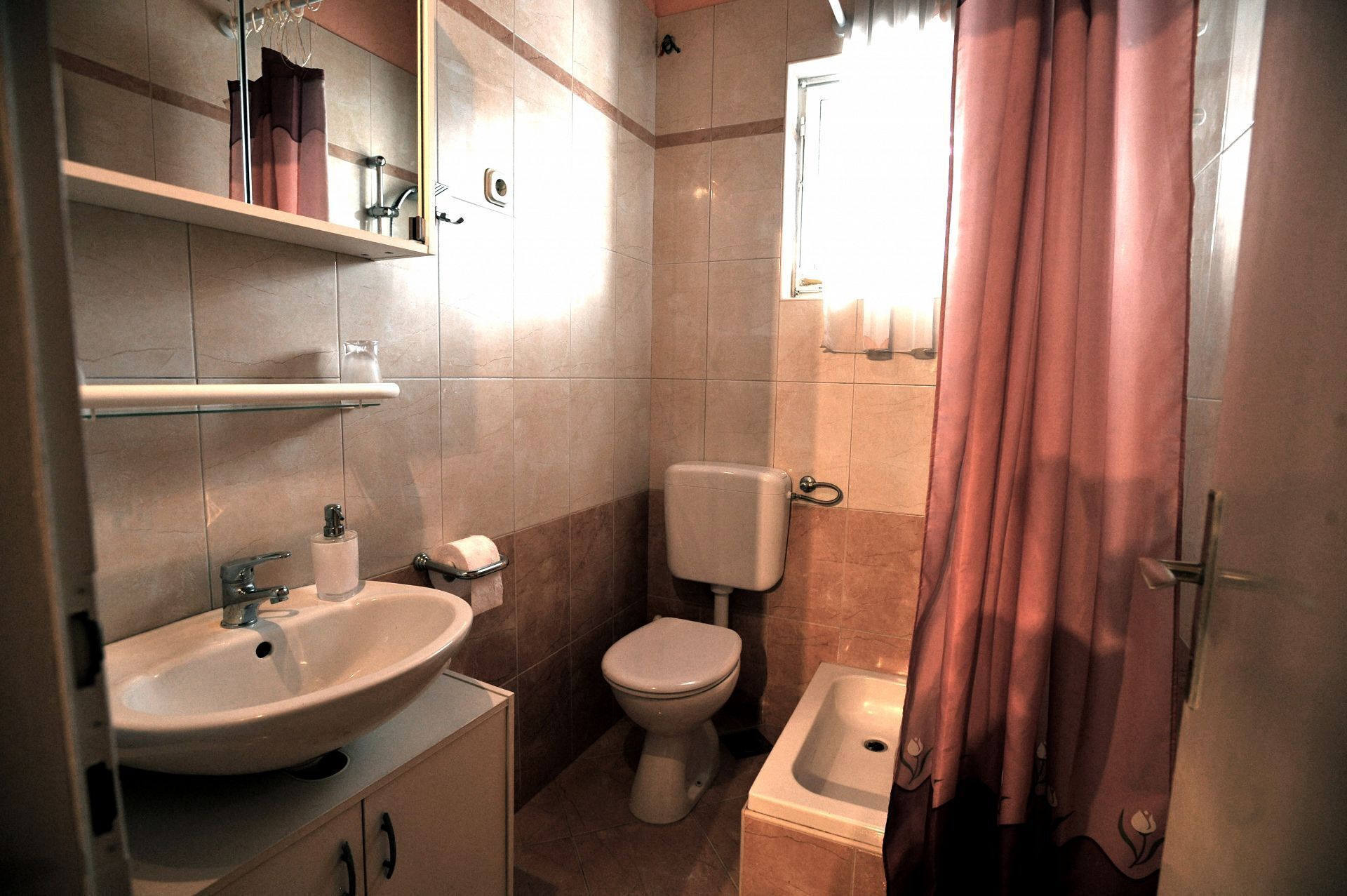 A bathroom with a sink, toilet, and shower area.