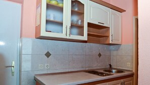 A kitchen with a countertop, sink, cabinets, and a door. - Apartments Virena (Makarska)