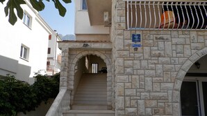 A stone staircase leading to an apartment entrance with a metal railing and a sign indicating the apartment number. - Apartments Virena (Makarska)