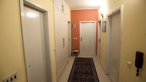 A narrow hallway with white doors on both sides, a patterned rug on the floor, and a small table with items on it. - Apartments Virena (Makarska)