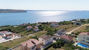 A coastal residential area with houses, a swimming pool, and a clear view of the sea. - Apartments Marietta (Razanac)