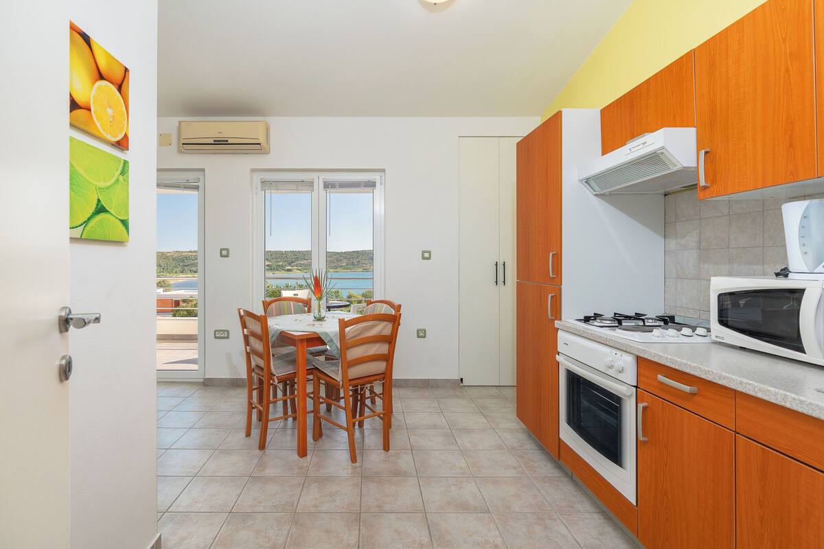 Una cocina con armarios de madera, estufa a gas, microondas y un comedor con mesa y sillas.