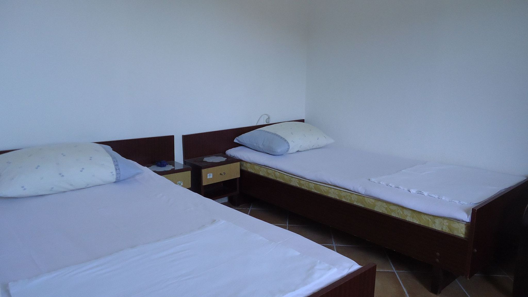 A twin room with two single beds, each with a pillow and a nightstand.