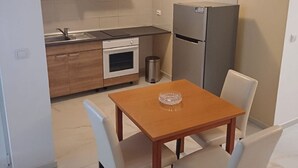 Eine kleine Küche mit Esstisch und Stühlen, einem Kühlschrank und einem Herd.