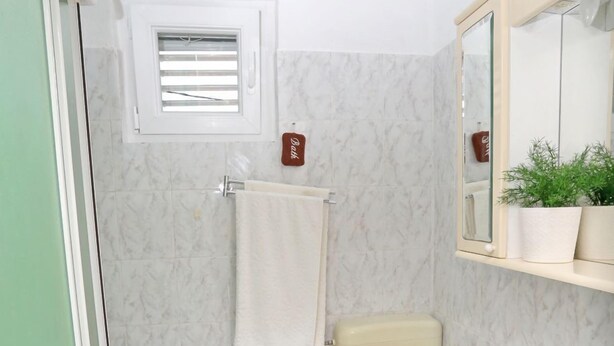 Baño con inodoro, lavamanos y una ventana pequeña.