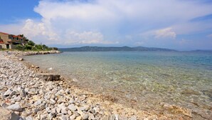 Una playa rocosa con agua cristalina y una vista distante de colinas.