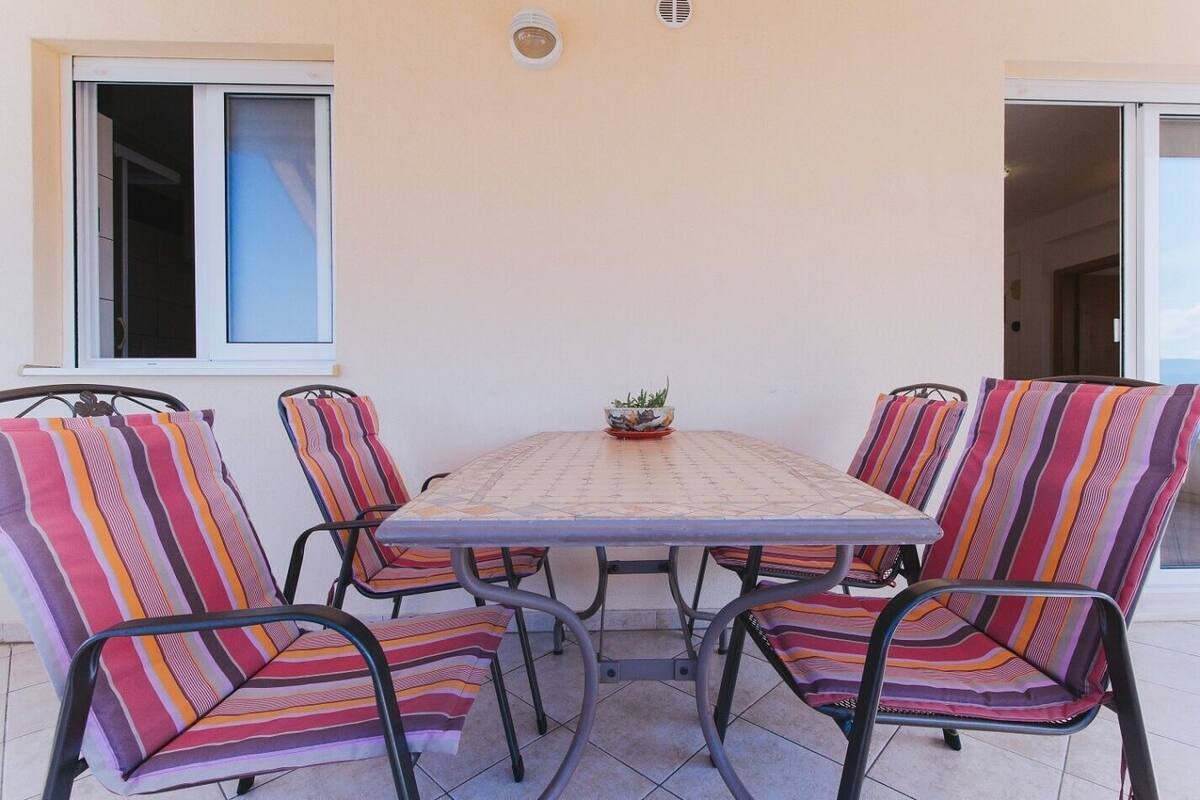 An outdoor patio with a table and six chairs, each with striped cushions.
