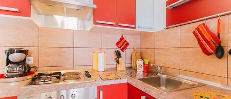A kitchen with red cabinets, a gas stove, a coffee maker, and various kitchen utensils.