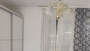 Une chambre à coucher avec un lit, un canapé, un lustre et une fenêtre avec des rideaux.