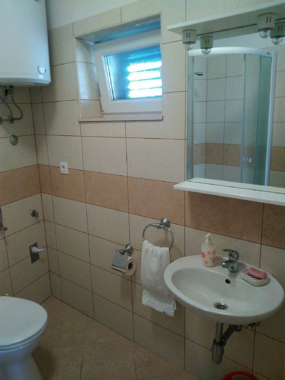 A bathroom with a toilet, sink, and window.