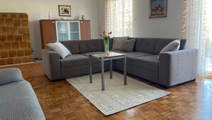 Un salon avec un canapé gris, une petite table sur laquelle est posé un vase de fleurs, un tapis à motifs et un mur dont le motif rappelle celui d’un mur de briques.