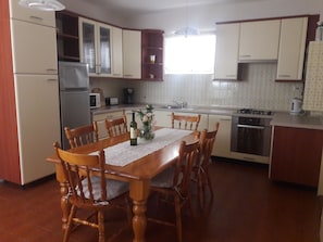 A compact kitchen with a dining table, chairs, a refrigerator, a microwave, a stove, and a sink. - Apartment Renci (Biograd na Moru)
