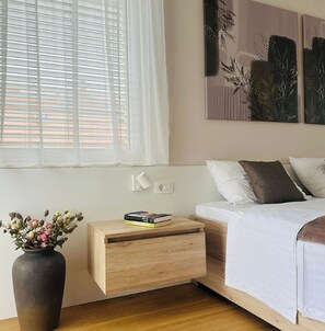 A bedroom with a bed, bedside table, and a vase of flowers. - Apartment Renci (Biograd na Moru)