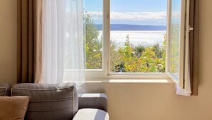 A room with a sofa, a window with curtains, and a view of the sea. - Apartment Ante (Starigrad)