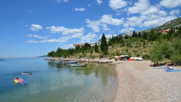 A beach with clear water, boats, and umbrellas. - Apartment Ante (Starigrad)