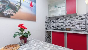 A kitchen with a tiled backsplash, a red cabinet, a sink, and a potted plant. - Apartments Boro (Dugi Rat)