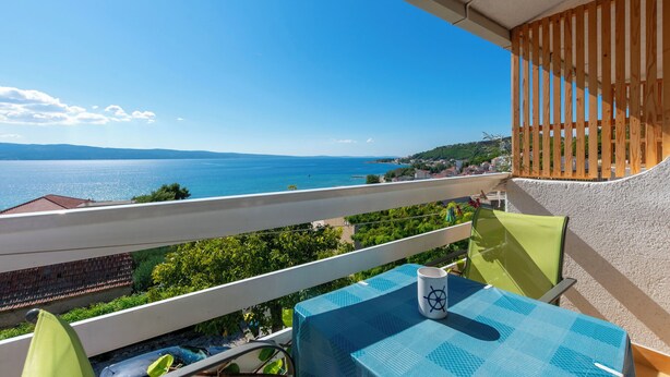 A balcony with a view of the sea, a table with a chair, and a wooden railing. - Apartments Boro (Dugi Rat)