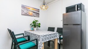 A compact kitchen with a refrigerator, a microwave, and a dining area with a table and chairs. - Apartments Boro (Dugi Rat)