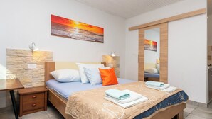A bedroom with a bed, bedside tables, a nightstand, a mirror, and a painting of a sunset. - Apartments Boro (Dugi Rat)
