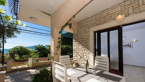 A balcony with a table and chairs, a bottle of wine, and a view of the sea. - Apartment Bareta (Okrug)