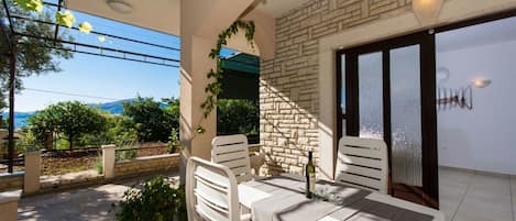 A balcony with a table and chairs, a bottle of wine, and a view of the sea.