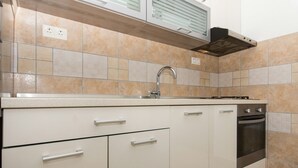 A kitchen with white cabinets, a stainless steel sink, and an oven. - Apartment Bareta (Okrug)