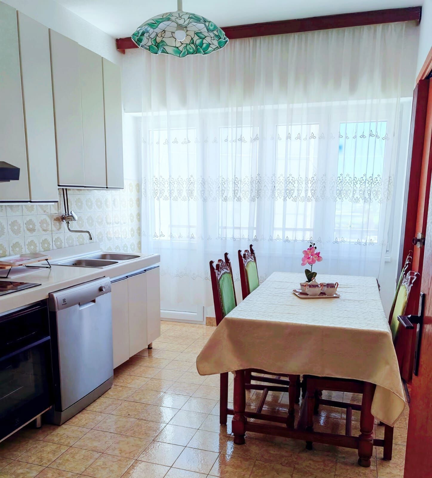 A kitchen with a dishwasher, a sink, and a dining area with a table and chairs.