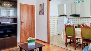 A living room with a TV, wooden cabinet, and a table with flowers. - Apartment Gordana (Kastela)