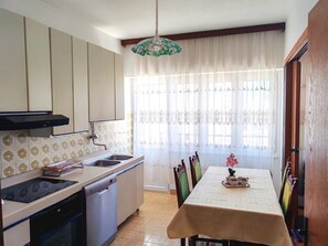 A kitchen with a dishwasher, stove, sink, and a dining table with chairs. - Apartment Gordana (Kastela)