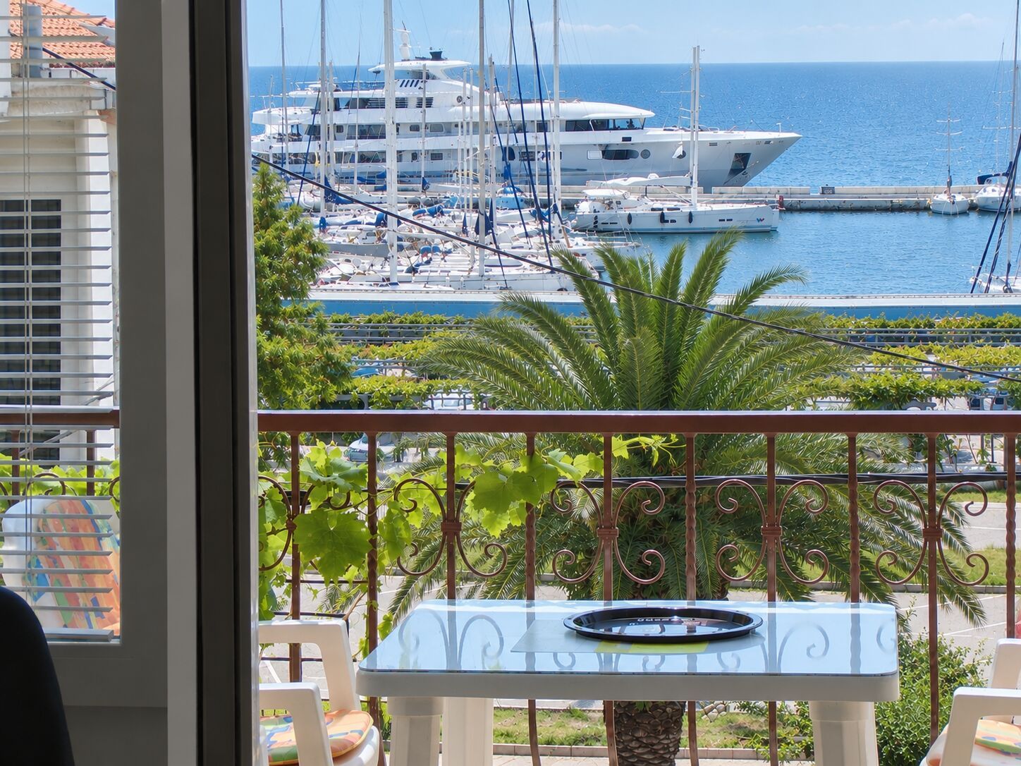 Een balkon met uitzicht op een jachthaven, waar verschillende jachten liggen aangemeerd.